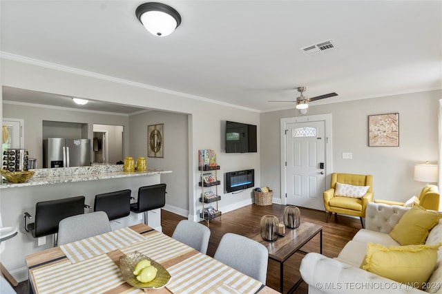 living room with dark wood-type flooring, crown molding, and ceiling fan