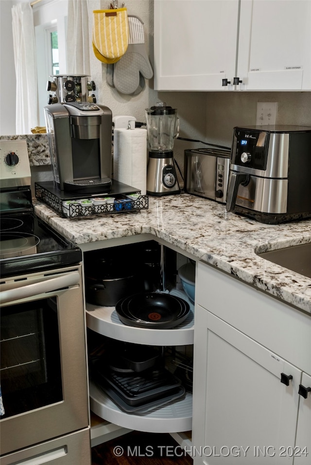 kitchen featuring electric stove, light stone countertops, and white cabinets