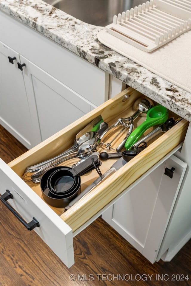 details featuring white cabinetry, dark hardwood / wood-style floors, and light stone counters