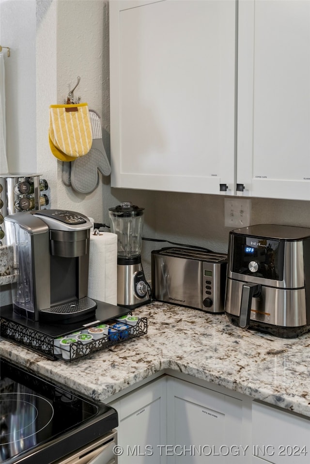 kitchen with white cabinetry, light stone counters, and range with electric stovetop