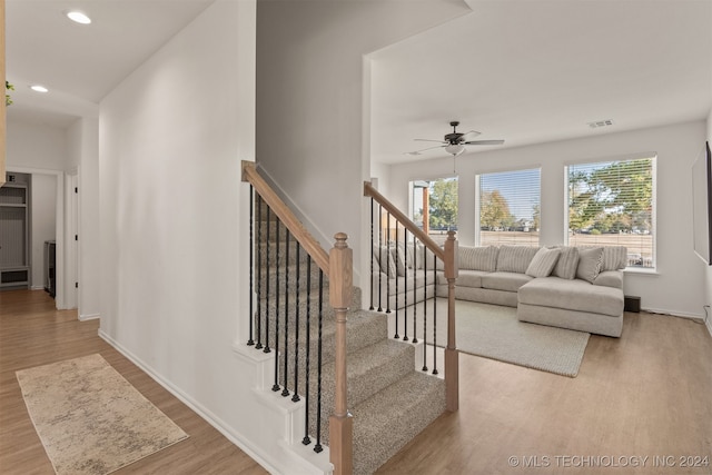 stairs featuring ceiling fan, a healthy amount of sunlight, and hardwood / wood-style floors