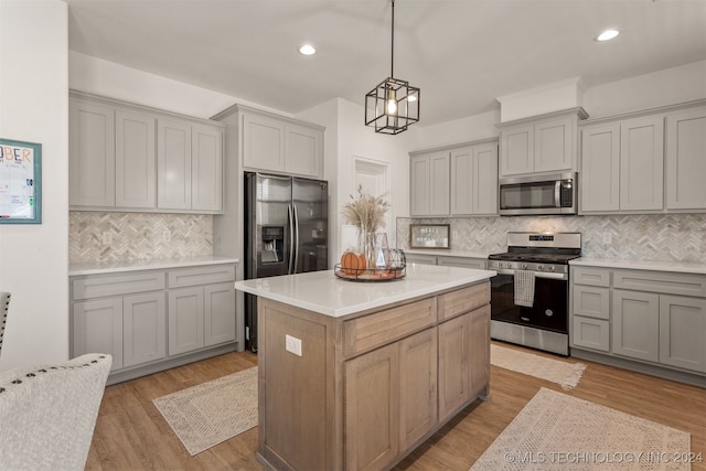 kitchen featuring tasteful backsplash, appliances with stainless steel finishes, a center island, light hardwood / wood-style floors, and decorative light fixtures