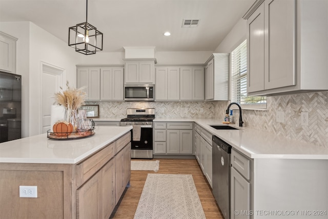 kitchen featuring appliances with stainless steel finishes, decorative light fixtures, sink, and gray cabinetry