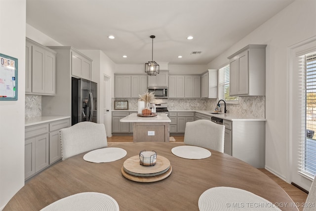 kitchen featuring appliances with stainless steel finishes, pendant lighting, a kitchen island, and gray cabinets