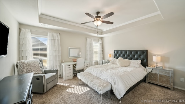 carpeted bedroom with a tray ceiling and ceiling fan