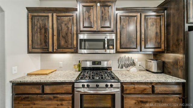 kitchen with light stone countertops, stainless steel appliances, and dark brown cabinets