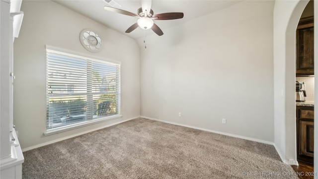 empty room with vaulted ceiling, carpet floors, and ceiling fan