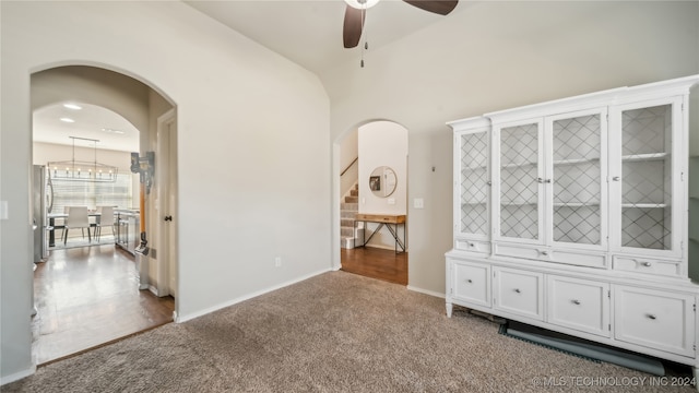 carpeted spare room with ceiling fan with notable chandelier