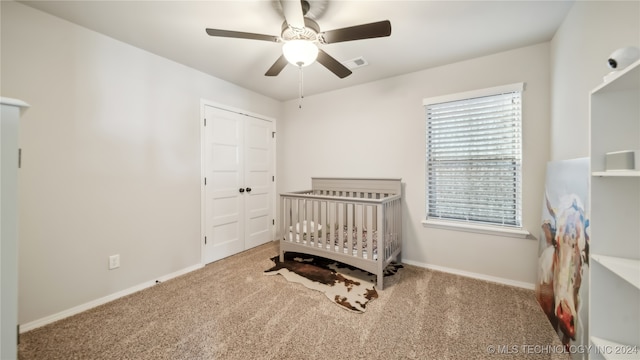 carpeted bedroom featuring a closet, a crib, and ceiling fan