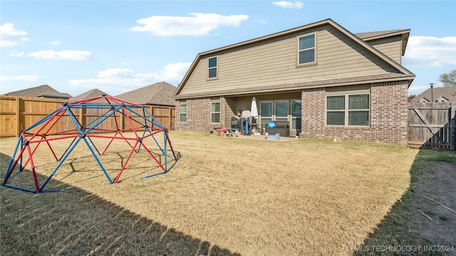 back of house with a patio area and a lawn