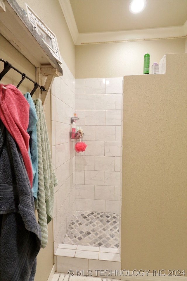 bathroom featuring ornamental molding and tiled shower