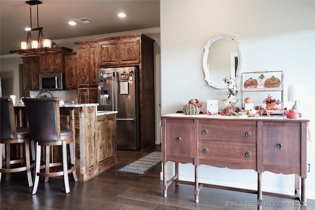 kitchen featuring stainless steel appliances, a center island with sink, hanging light fixtures, crown molding, and dark wood-type flooring