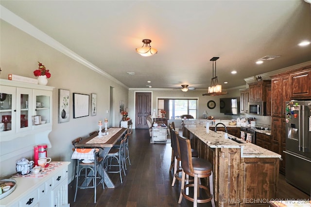 kitchen featuring stainless steel appliances, decorative light fixtures, dark hardwood / wood-style flooring, a breakfast bar, and ceiling fan