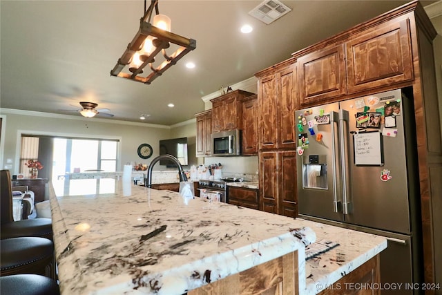 kitchen with ornamental molding, stainless steel appliances, decorative light fixtures, a large island, and a kitchen bar