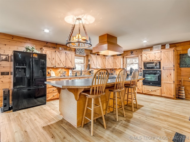 kitchen featuring black appliances, wood walls, light wood-type flooring, and a kitchen island