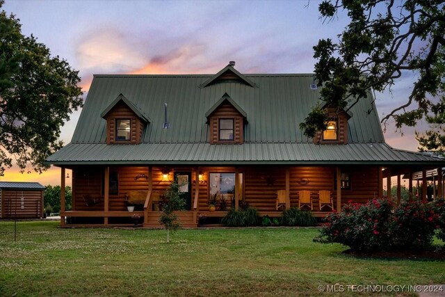 back house at dusk featuring a lawn and a porch