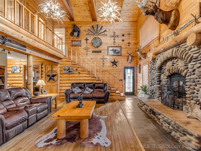 living room featuring a stone fireplace, an inviting chandelier, and high vaulted ceiling