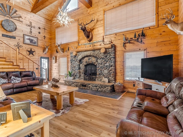 living area with wood walls, beamed ceiling, a stone fireplace, and wood finished floors