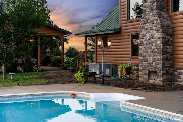 pool with central AC unit, a patio, and an outdoor stone fireplace