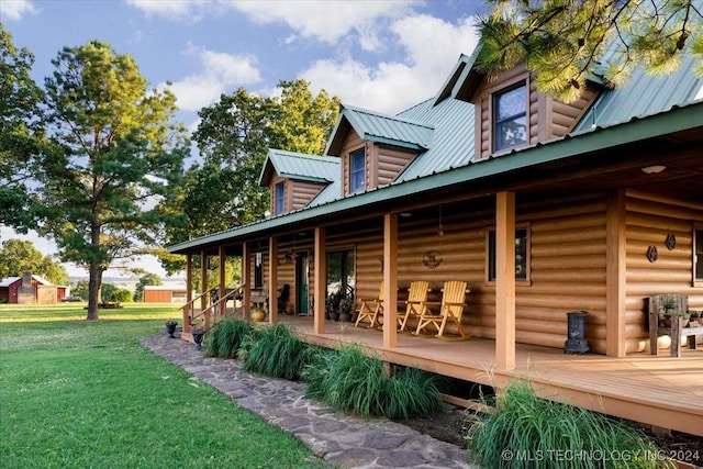 rear view of house with covered porch, metal roof, and a lawn