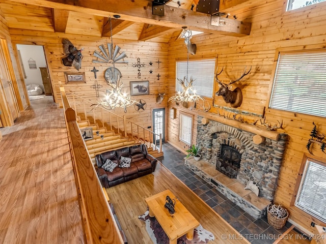 living room with wood walls, a fireplace, beam ceiling, and wood finished floors