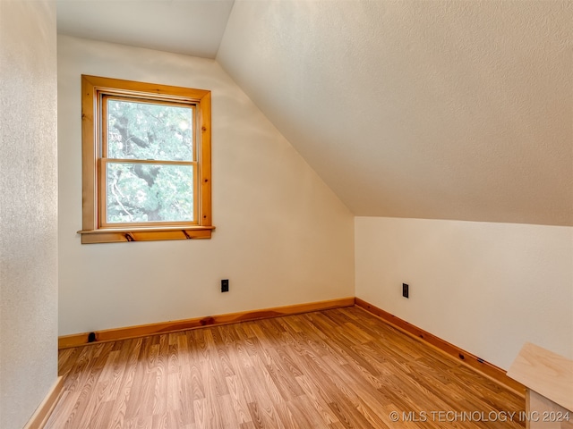 additional living space featuring light hardwood / wood-style flooring and lofted ceiling