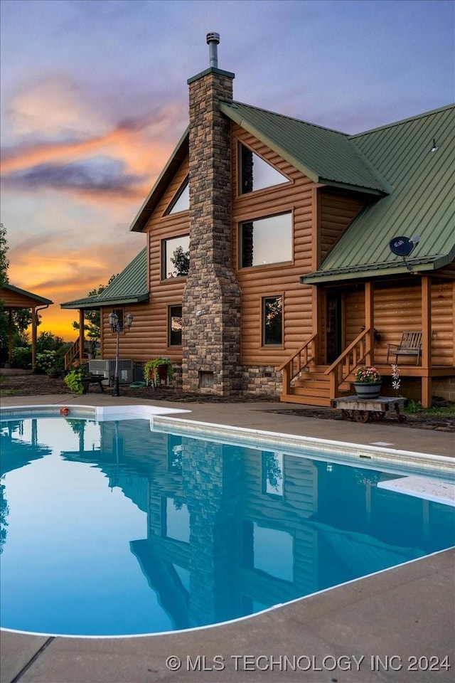 outdoor pool with a patio area and a diving board