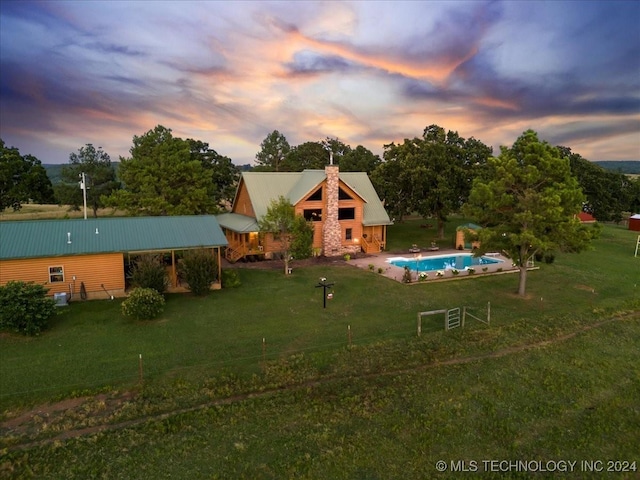 back of house with metal roof, a lawn, a chimney, and an outdoor pool