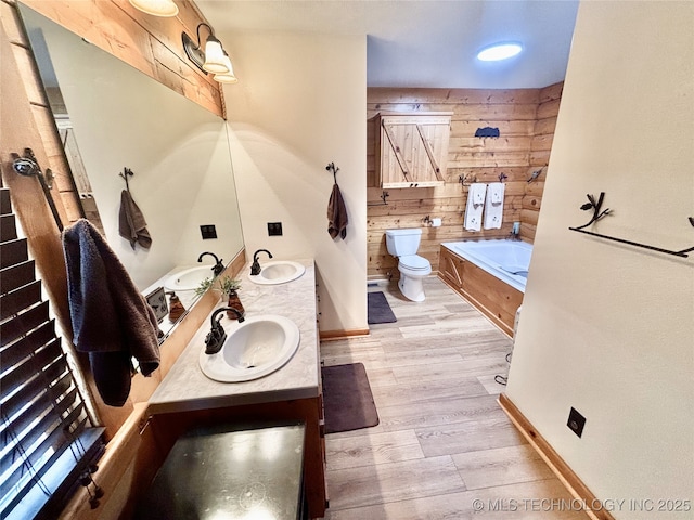 full bath with wooden walls, a sink, and wood finished floors