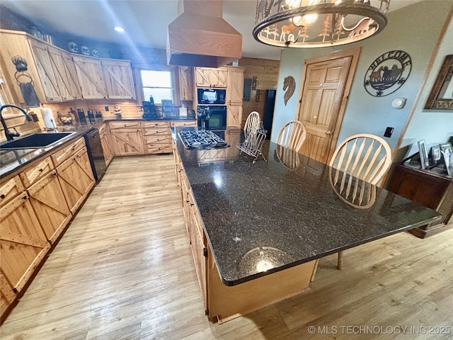 kitchen with a large island, custom exhaust hood, light wood-style flooring, a sink, and black appliances