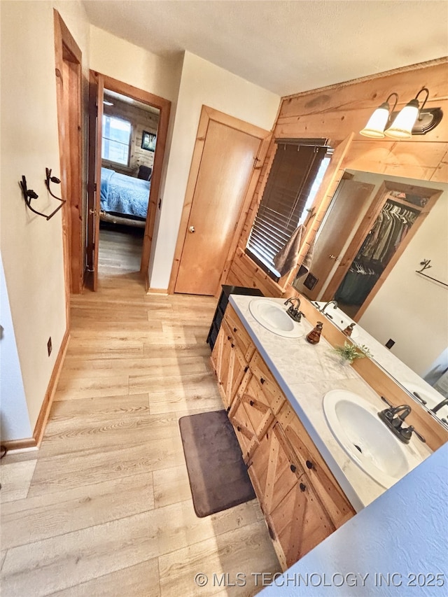 ensuite bathroom with ensuite bathroom, double vanity, wood finished floors, and a sink