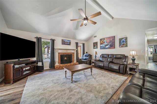 living room with ceiling fan, lofted ceiling with beams, a brick fireplace, and hardwood / wood-style floors