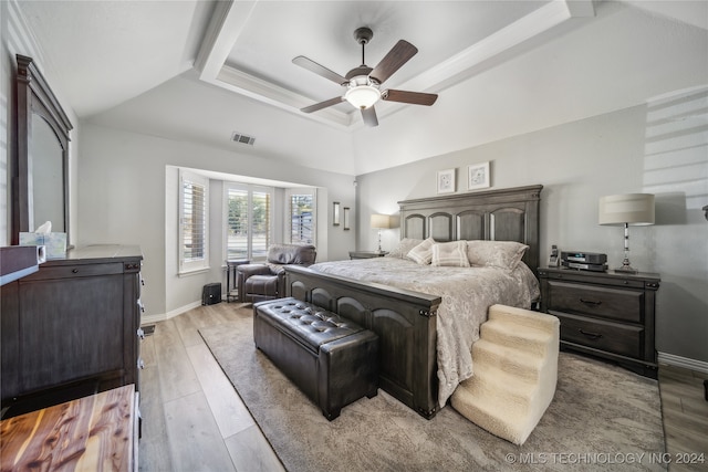 bedroom with ceiling fan, a raised ceiling, and light wood-type flooring