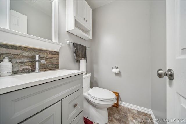 bathroom featuring toilet, vanity, and backsplash