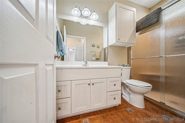 bathroom with a shower with door, vanity, and toilet