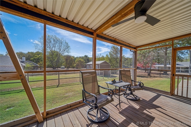 unfurnished sunroom featuring ceiling fan, a healthy amount of sunlight, and lofted ceiling with beams