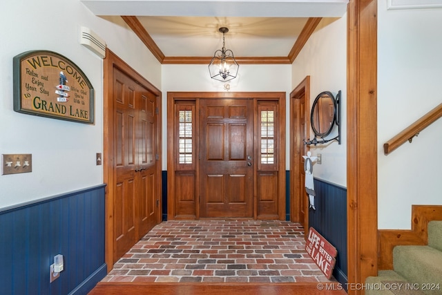 entrance foyer featuring ornamental molding, wooden walls, and a notable chandelier