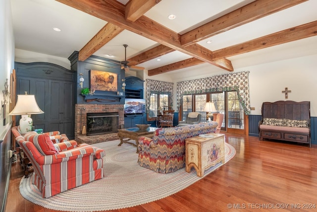 living room featuring beamed ceiling, wood-type flooring, and ceiling fan