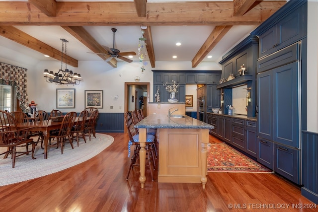 kitchen with blue cabinetry, beam ceiling, stone countertops, and dark wood-type flooring