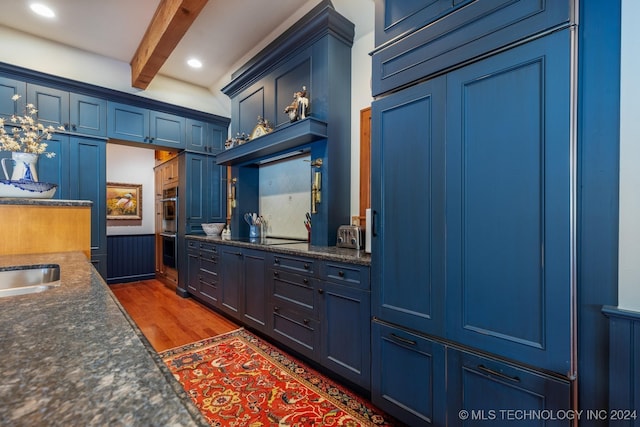 kitchen featuring black electric stovetop, double oven, beamed ceiling, dark wood-type flooring, and blue cabinetry