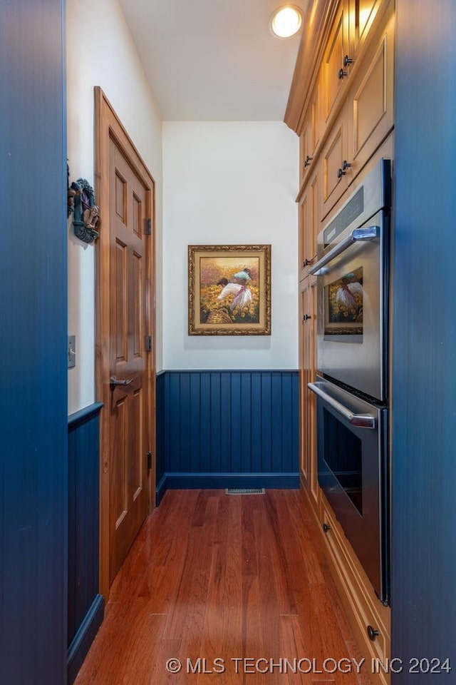 kitchen with double oven and dark hardwood / wood-style floors