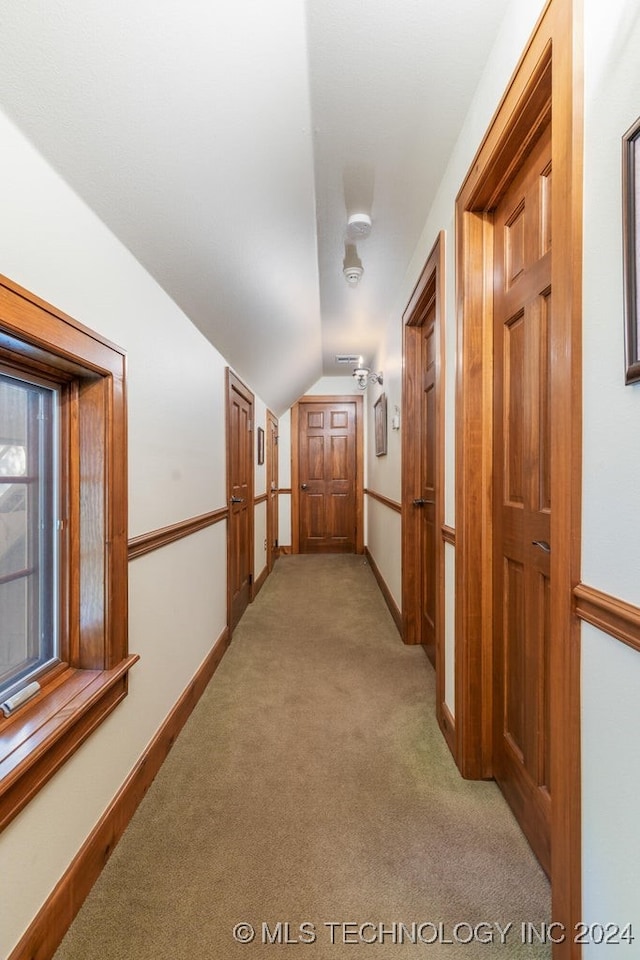 hall with light colored carpet and vaulted ceiling