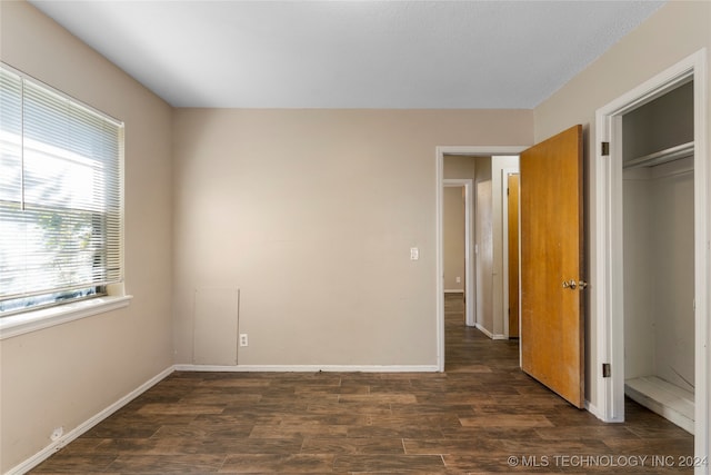 unfurnished bedroom with a closet and dark hardwood / wood-style floors