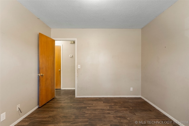 empty room featuring a textured ceiling and dark hardwood / wood-style floors