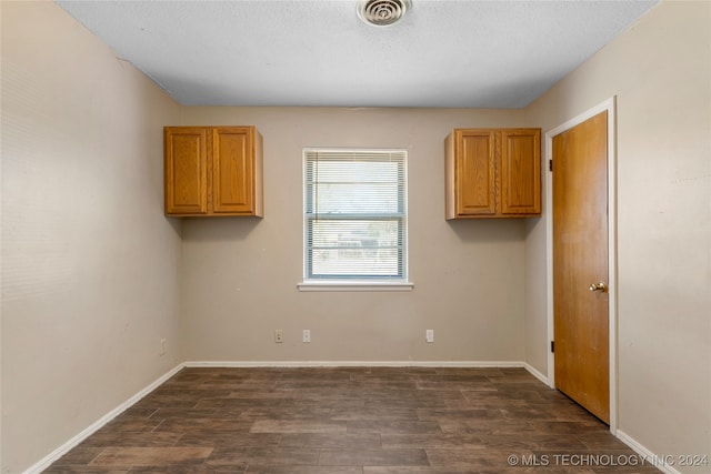 laundry area with dark hardwood / wood-style floors and a textured ceiling