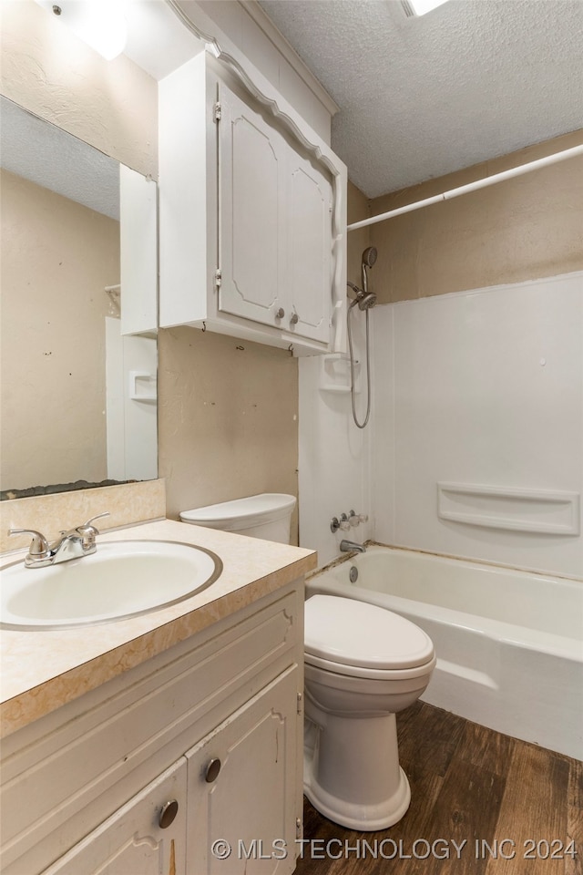 full bathroom with toilet, wood-type flooring, bathing tub / shower combination, vanity, and a textured ceiling