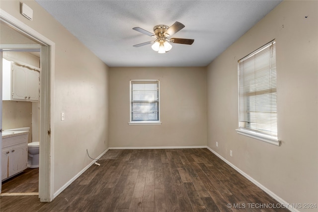 empty room featuring ceiling fan, a textured ceiling, and dark hardwood / wood-style floors