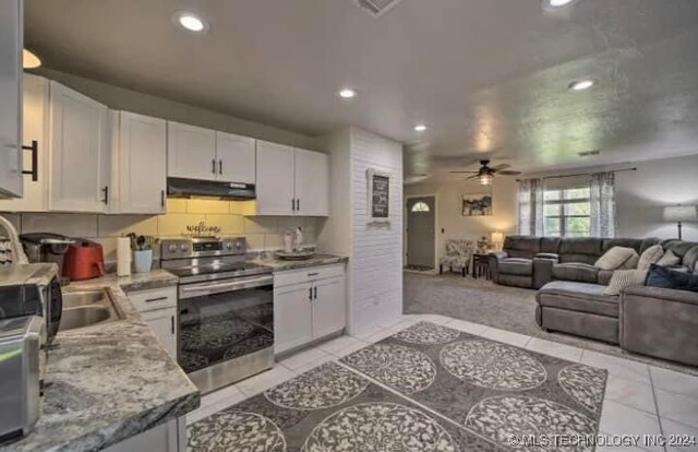 kitchen with light stone countertops, electric stove, ceiling fan, white cabinets, and light tile patterned floors