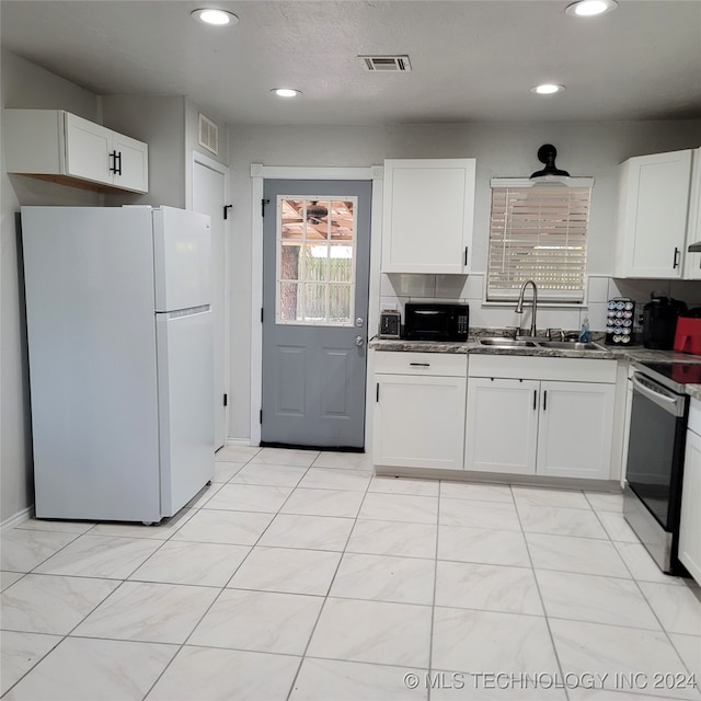 kitchen with stainless steel range oven, sink, white cabinetry, and white fridge