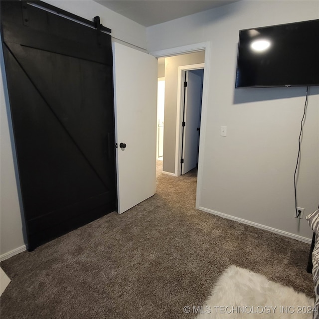 unfurnished bedroom featuring carpet and a barn door